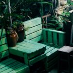 Charming outdoor garden seating area with green pallets and vintage watering can.