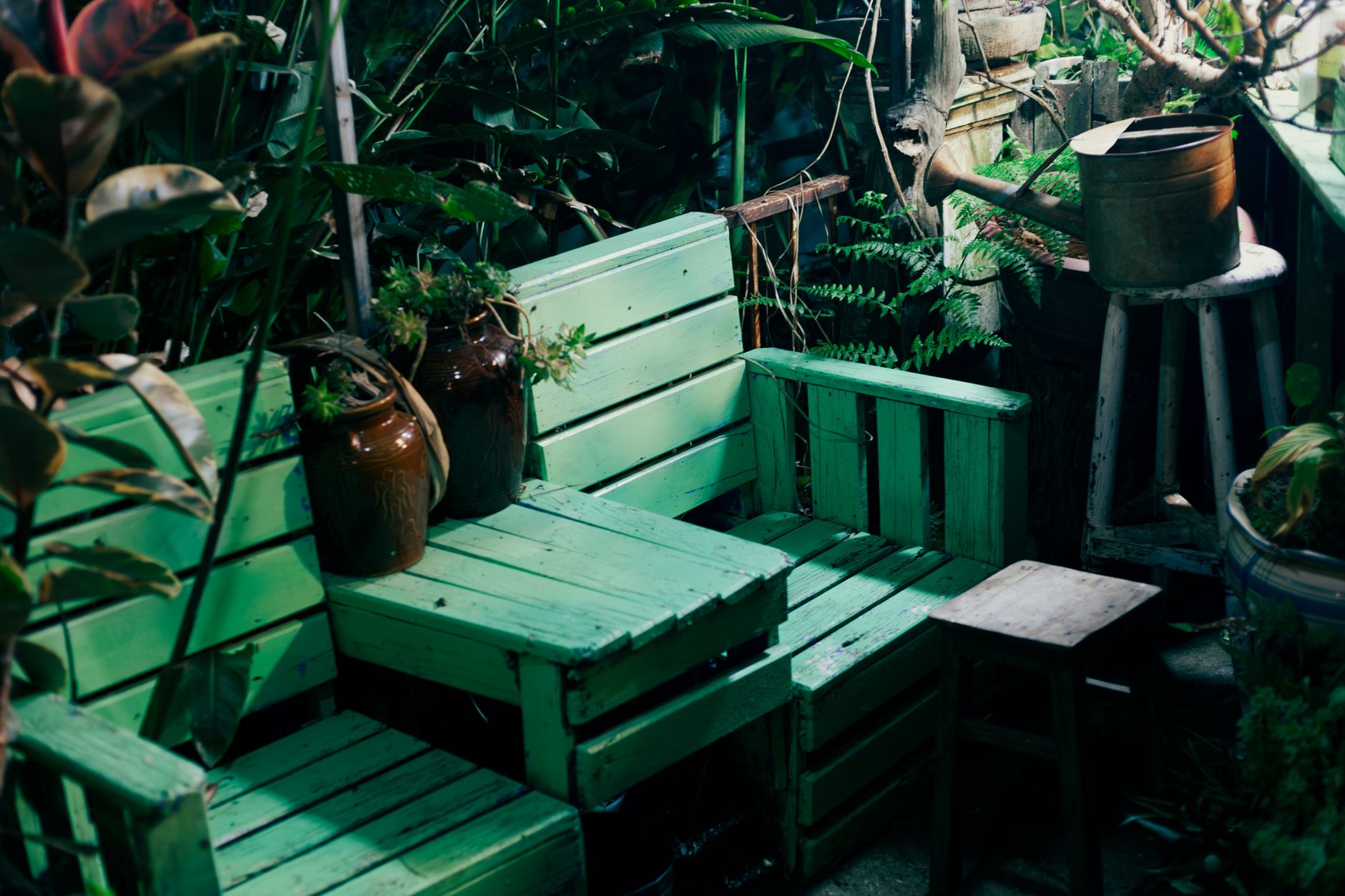 Charming outdoor garden seating area with green pallets and vintage watering can.